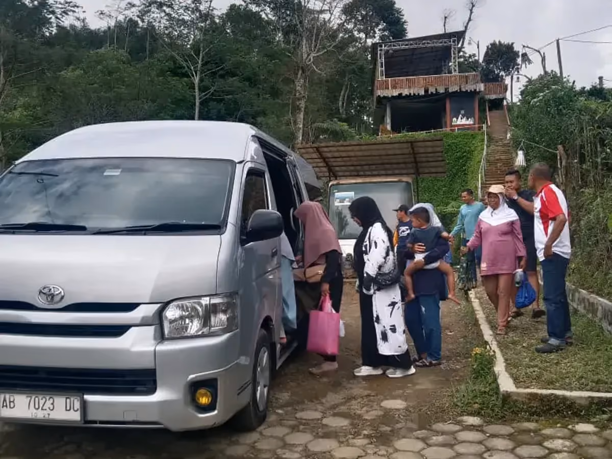 HiAce Commuter silver dengan penumpang naik di jalan batu di daerah pinggiran